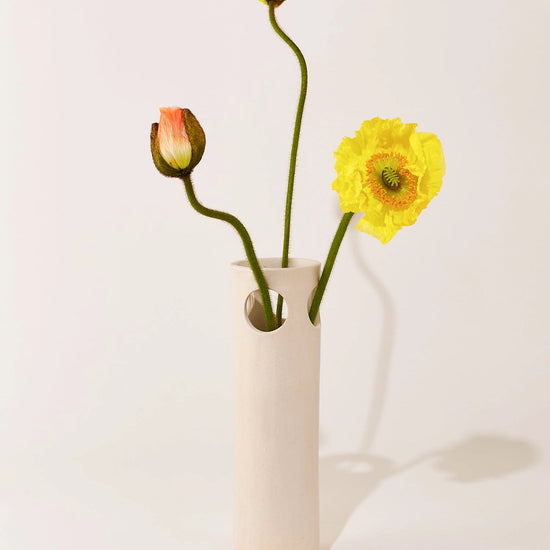 White vase with a yellow flower and buds on a light background