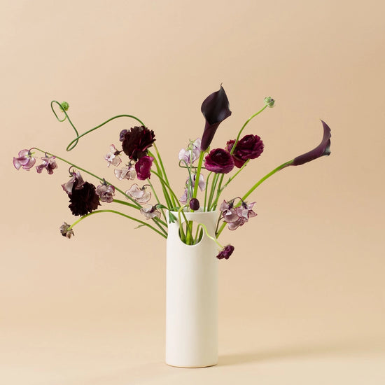 White vase with flowers on a beige background