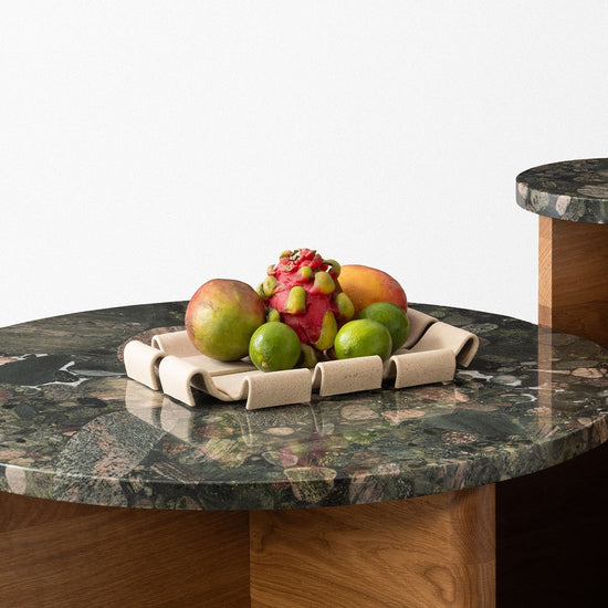 Modern coffee table with marble top and wooden base on a concrete floor.