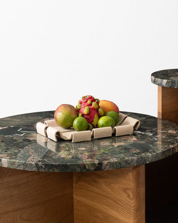 Modern coffee table with marble top and wooden base on a concrete floor.