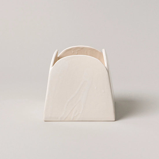 White ceramic vase with a textured surface on a light gray background