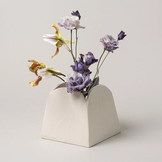 White geometric vase with flowers on a light gray background