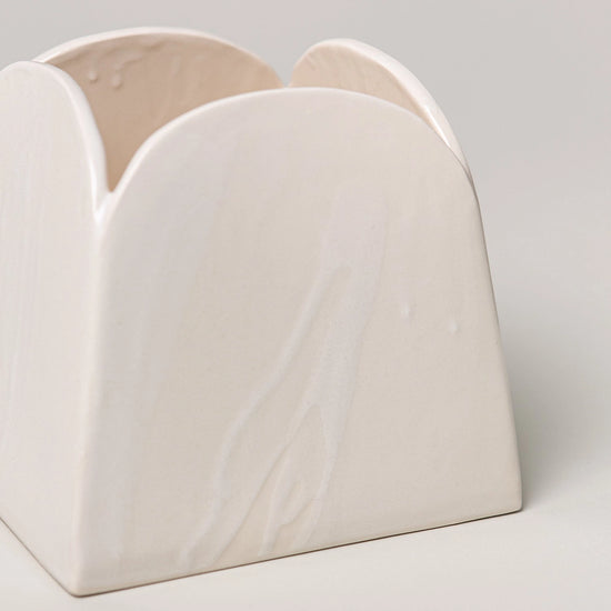 White ceramic vase with a geometric design on a light gray background