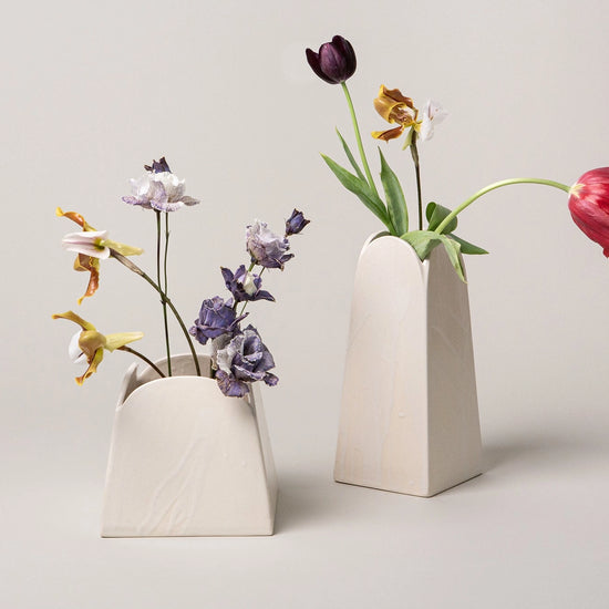 Two ceramic vases with flowers on a light background