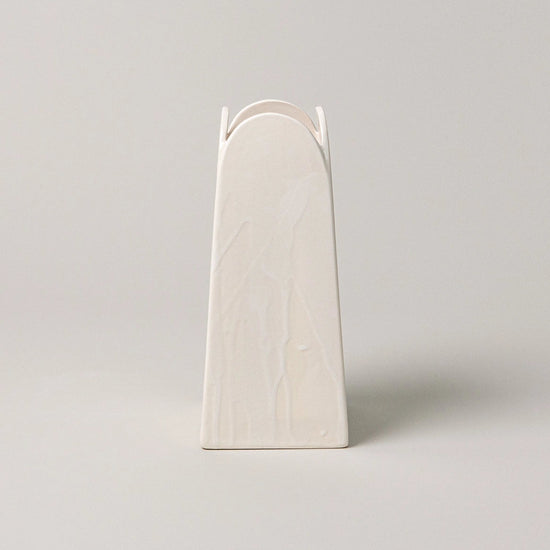 White ceramic vase with arch design on a light gray background
