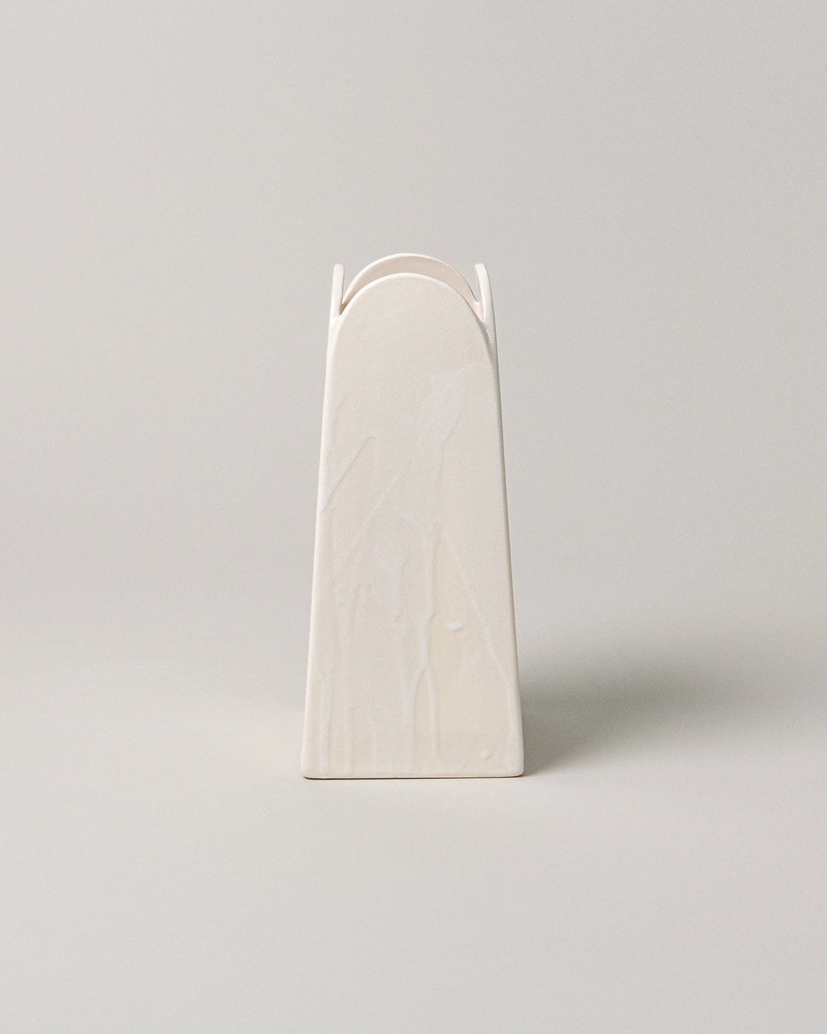 White ceramic vase with arch design on a light gray background