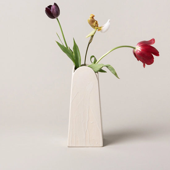 Minimalist vase with three tulips on a light gray background