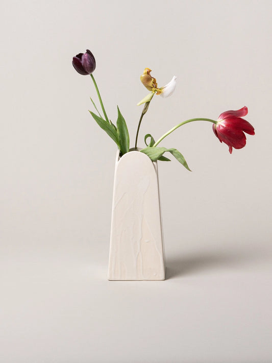 Minimalist vase with three tulips on a light gray background