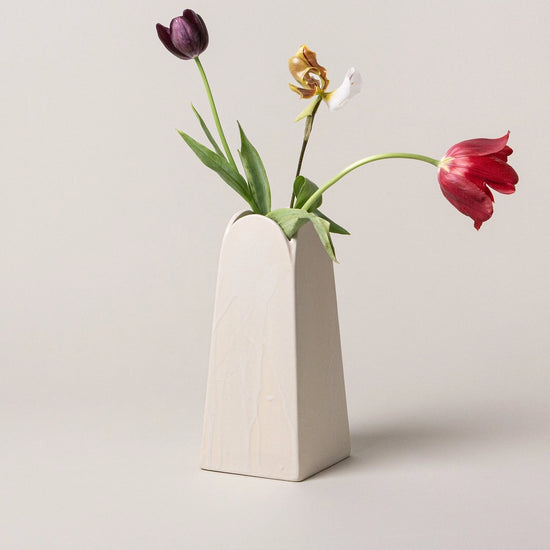 White vase with tulips on a light gray background