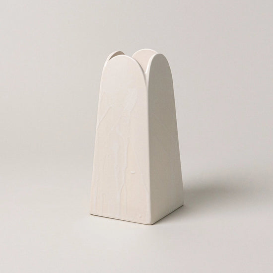 White ceramic vase with a unique design on a light gray background