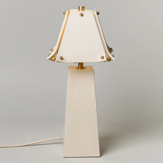 Table lamp with a white shade and beige base on a gray background