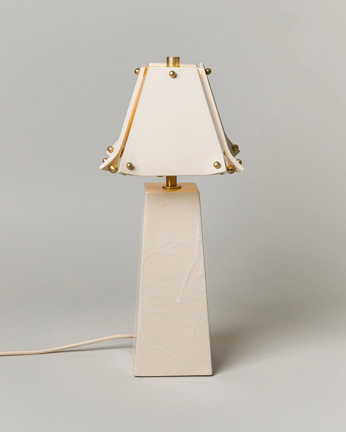 Table lamp with a white shade and beige base on a gray background
