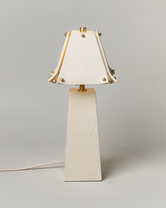 Table lamp with a white shade and beige base on a gray background