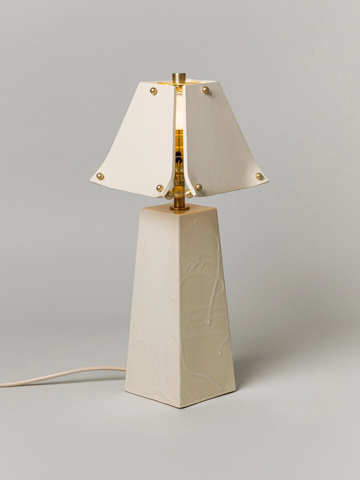 Table lamp with a white shade and beige base on a gray background