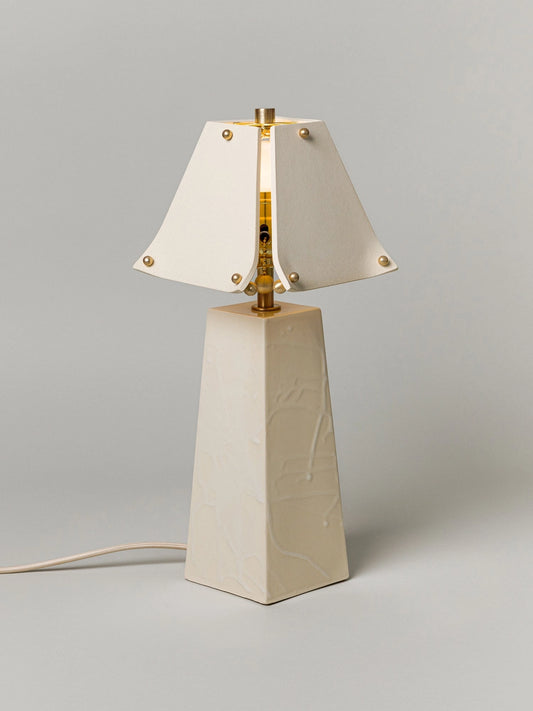Table lamp with a white shade and beige base on a gray background