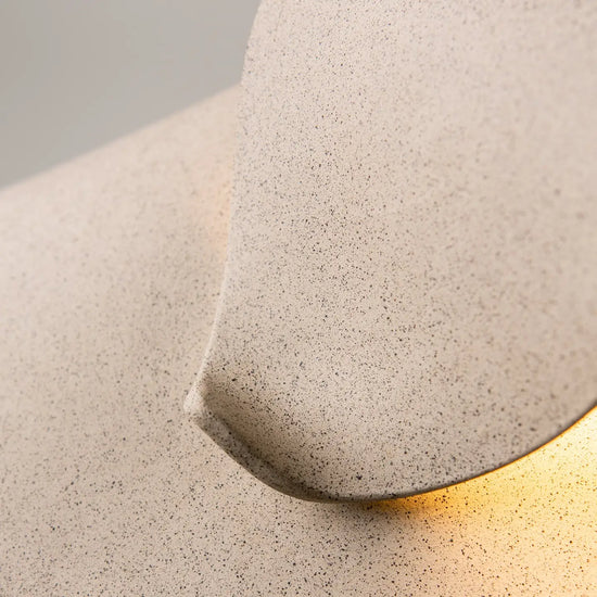 Close-up of a textured concrete wall light fixture with a gold interior.