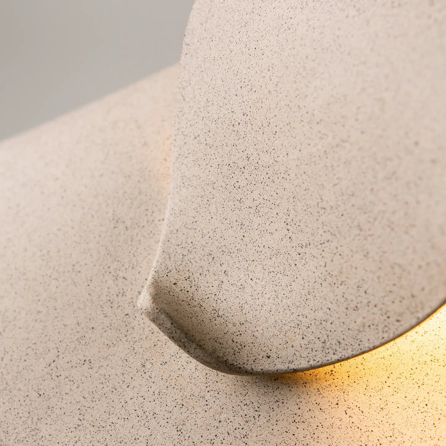 Close-up of a textured concrete wall light fixture with a gold interior.