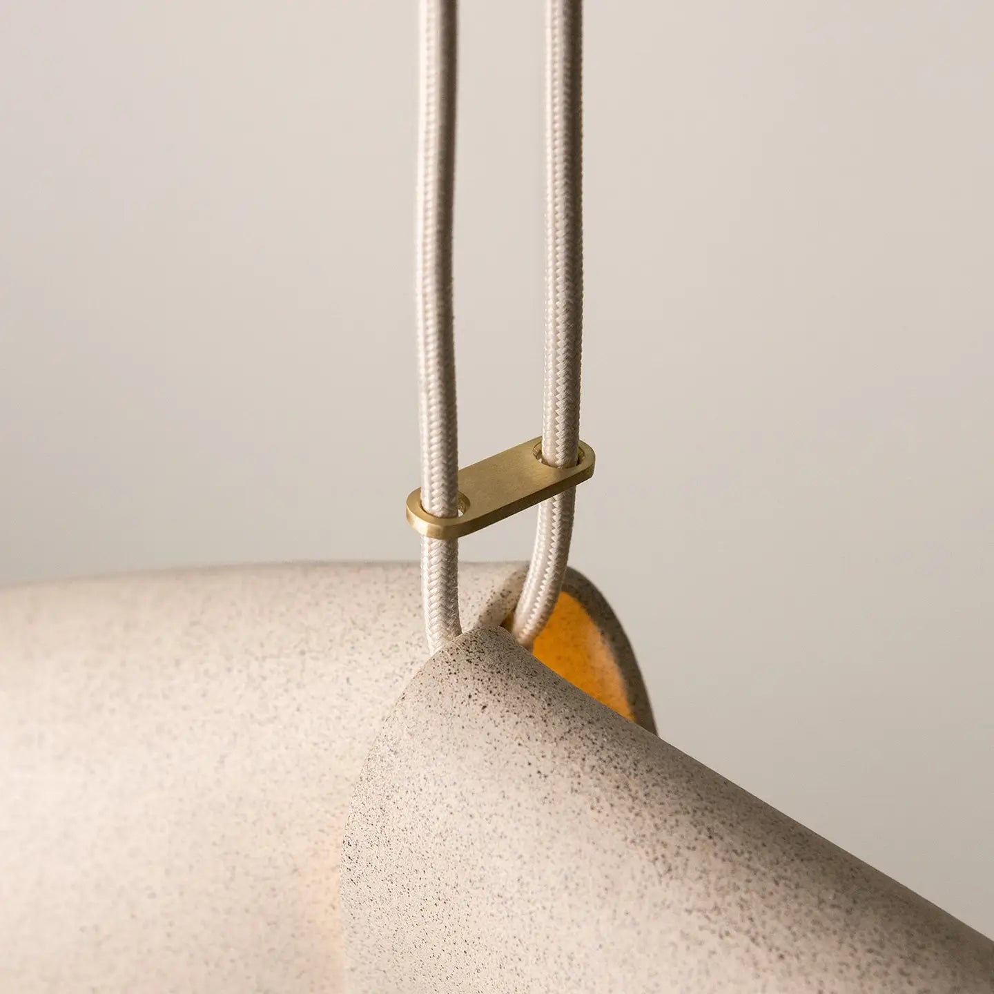 Close-up of a textured stone surface with a gold accent and white cord.