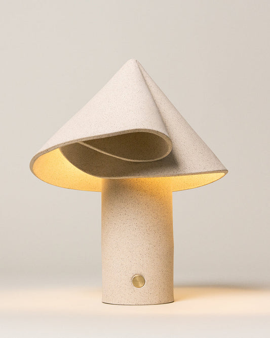 Sand-colored ceramic table lamp with a rounded base, photographed against a neutral background