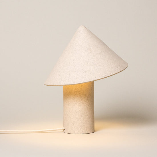 Small table lamp with a cone-shaped white shade on a light gray background