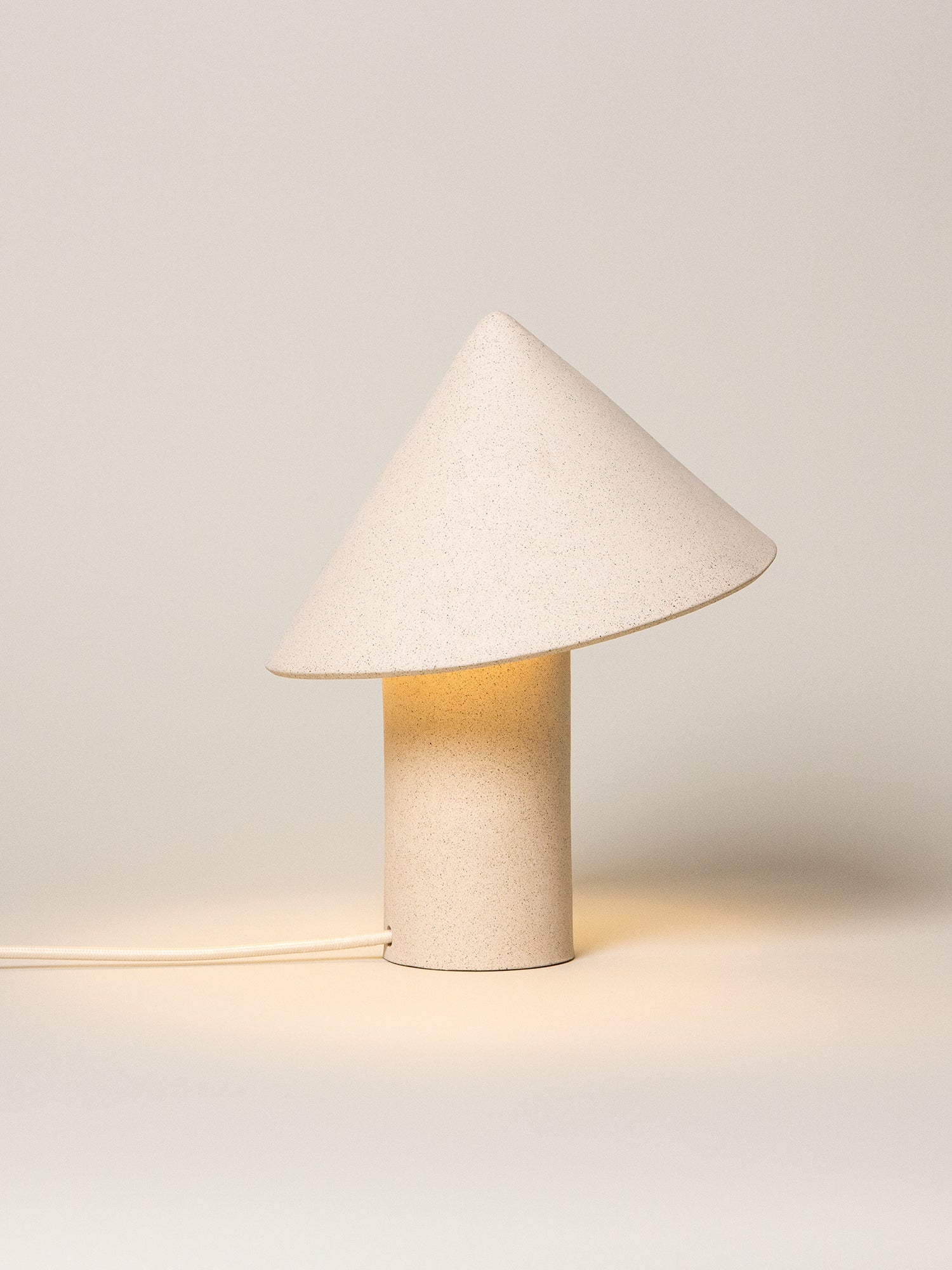 Small table lamp with a cone-shaped white shade on a light gray background