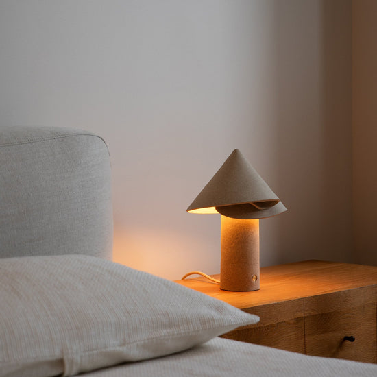 Bedroom scene with a bed and wooden nightstand featuring a lamp.