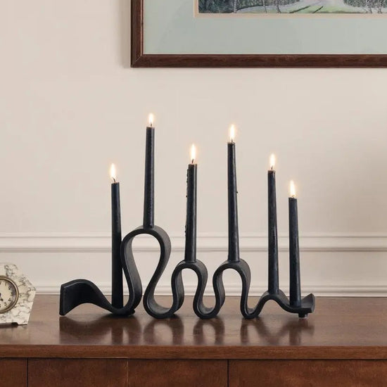 Decorative setup with candles, a clock, and a framed artwork on a wooden surface.