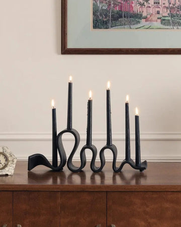 Decorative setup with candles, a clock, and a framed artwork on a wooden surface.