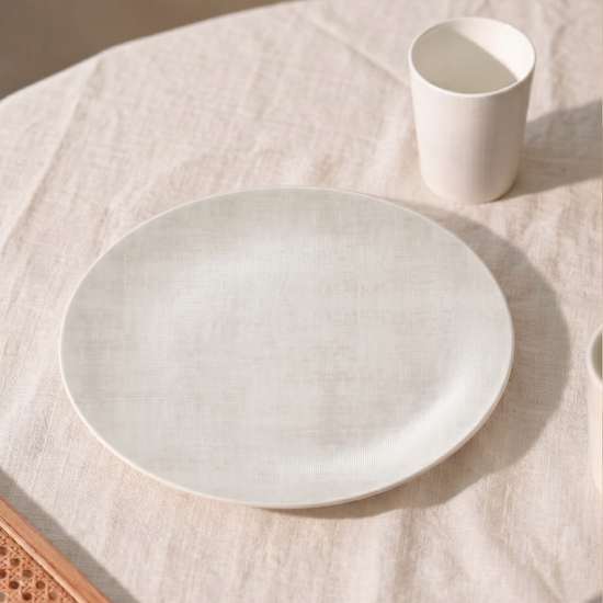 Ivory ceramic plate and cup on a textured surface