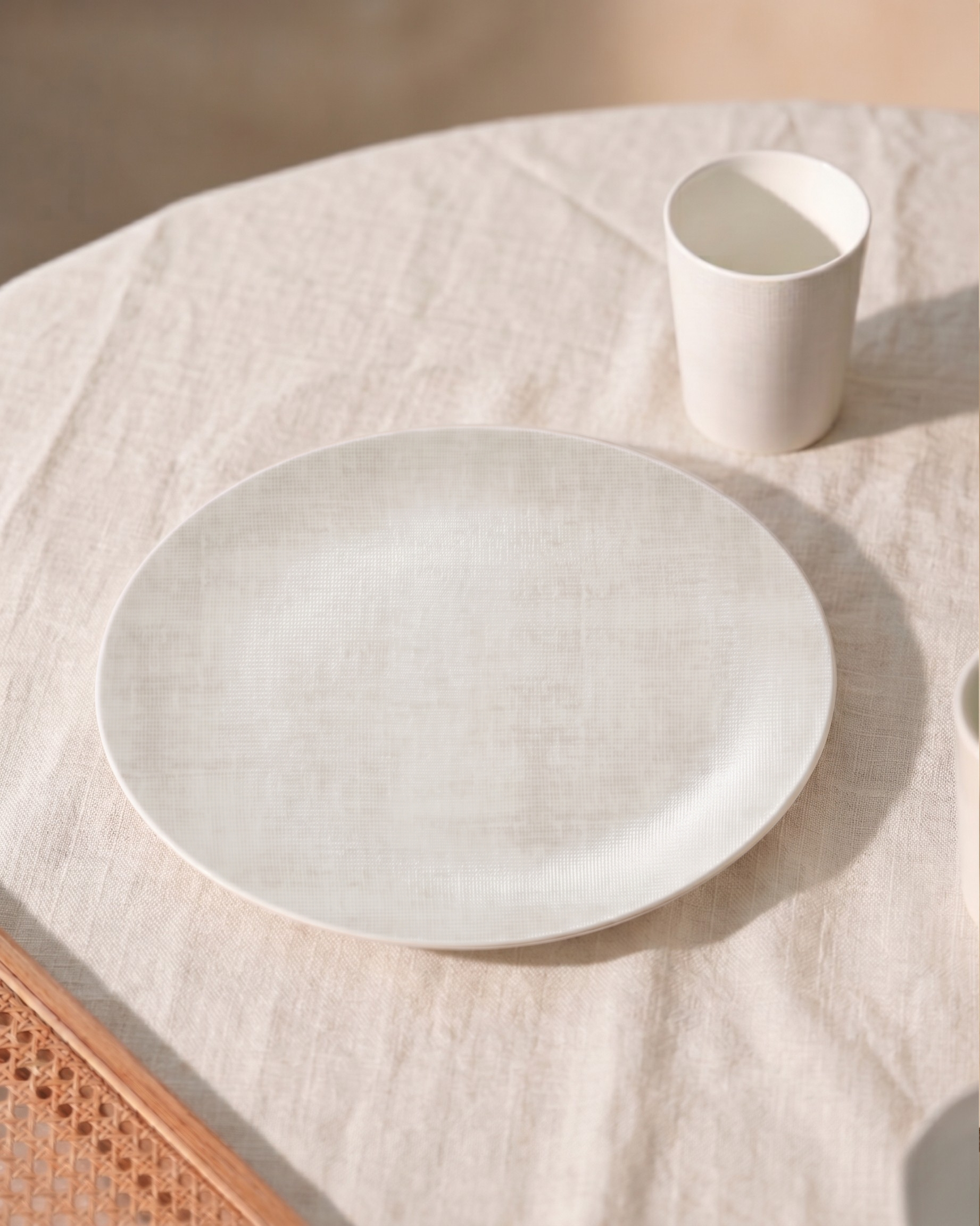 Ivory ceramic plate and cup on a textured surface