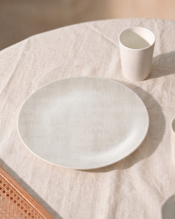 Ivory ceramic plate and cup on a textured surface