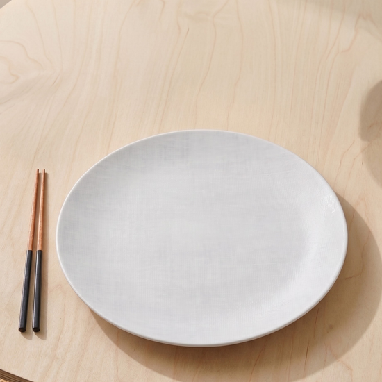 White plate on a wooden table with two chopsticks.