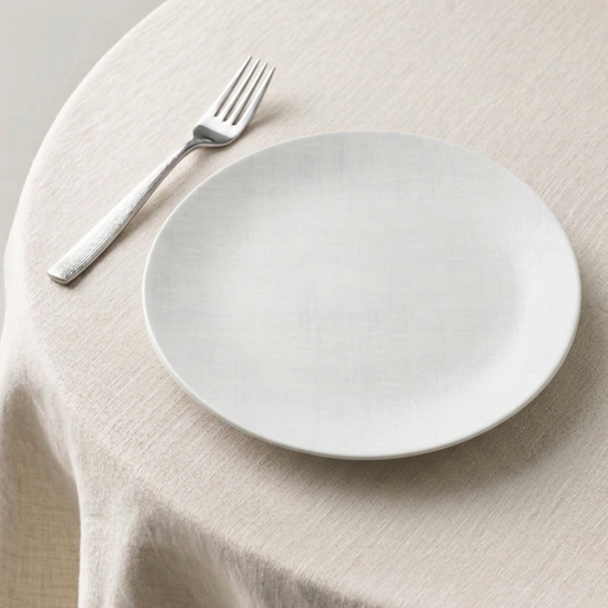 White plate and fork on a beige tablecloth