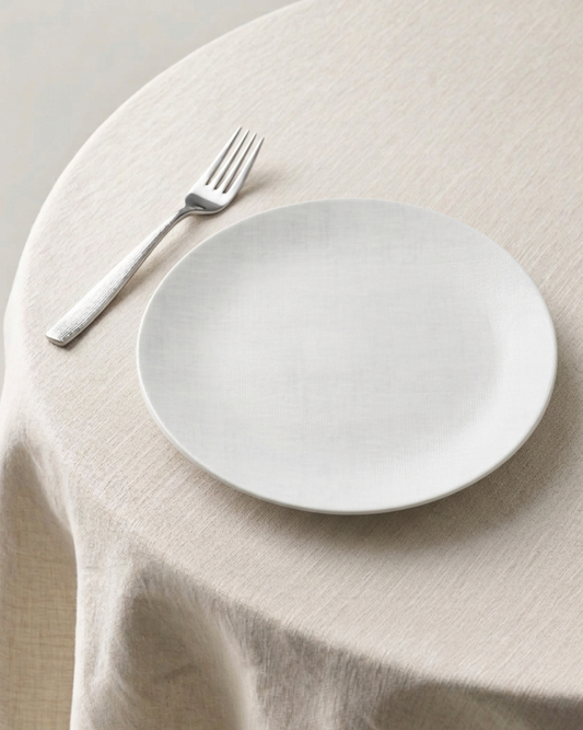 White plate and fork on a beige tablecloth