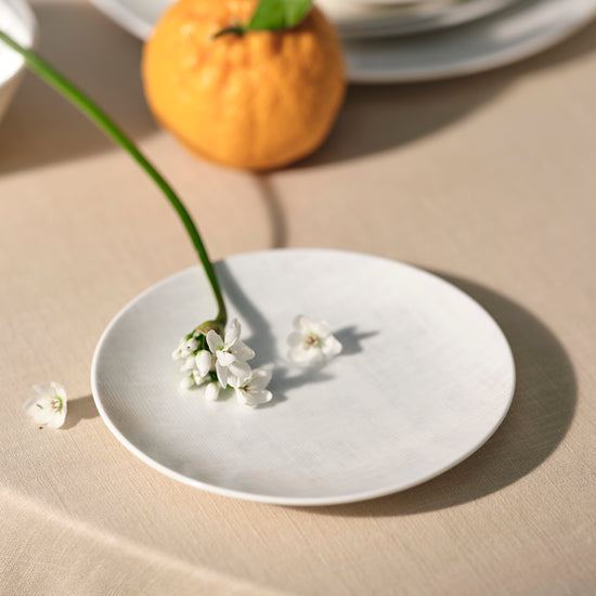 White ceramic plate with small white flowers on a beige surface