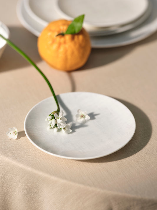 White ceramic plate with small white flowers on a beige surface
