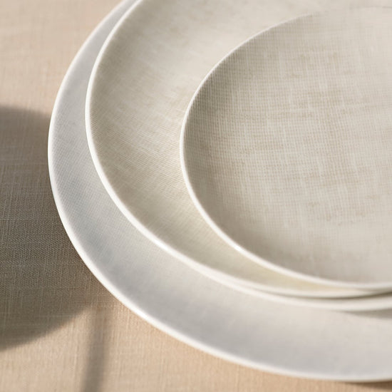Two beige ceramic plates stacked on a beige surface