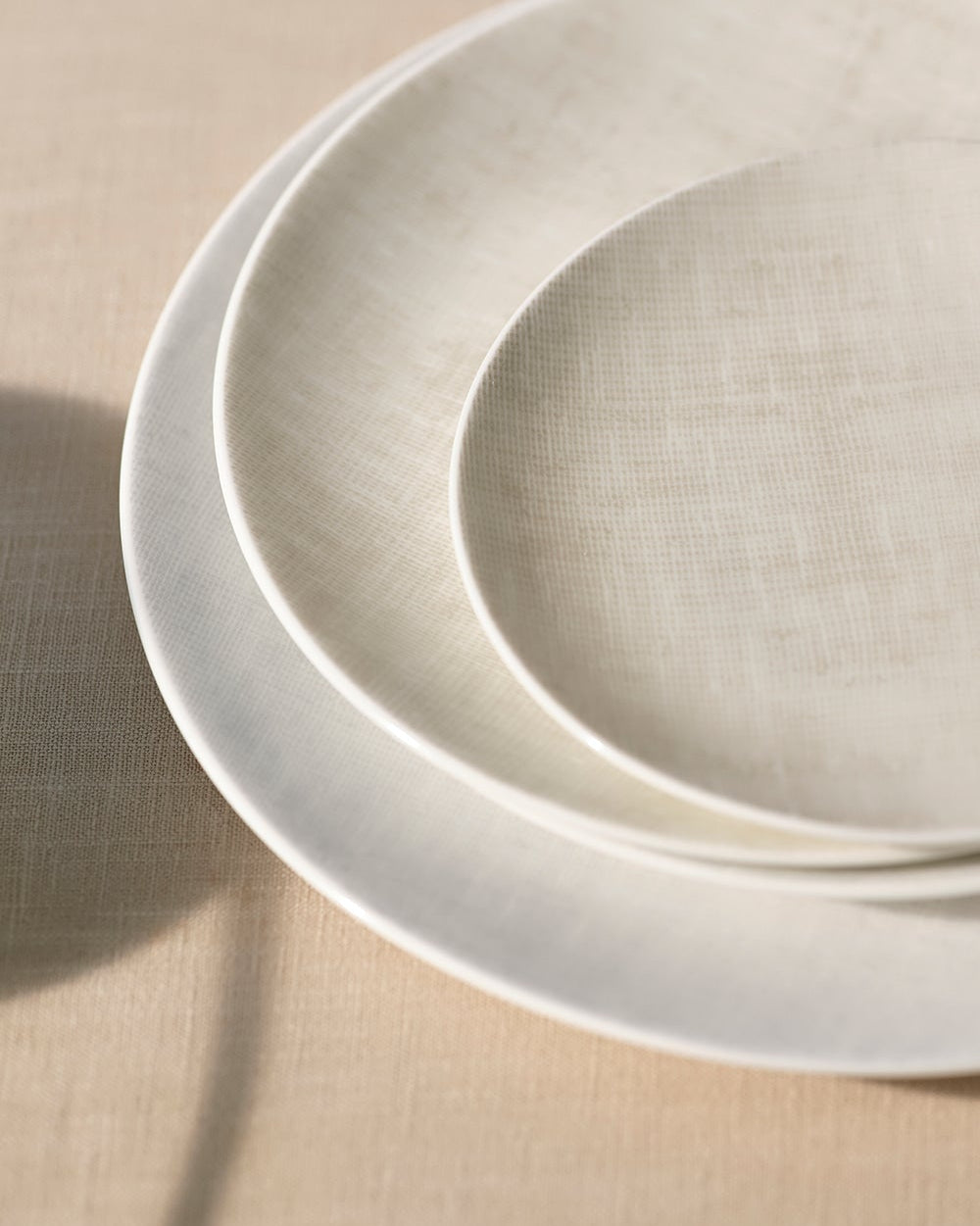 Two beige ceramic plates stacked on a beige surface
