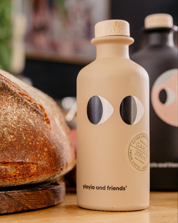 Loaf of bread on a wooden board with a beige bottle featuring black circular designs.