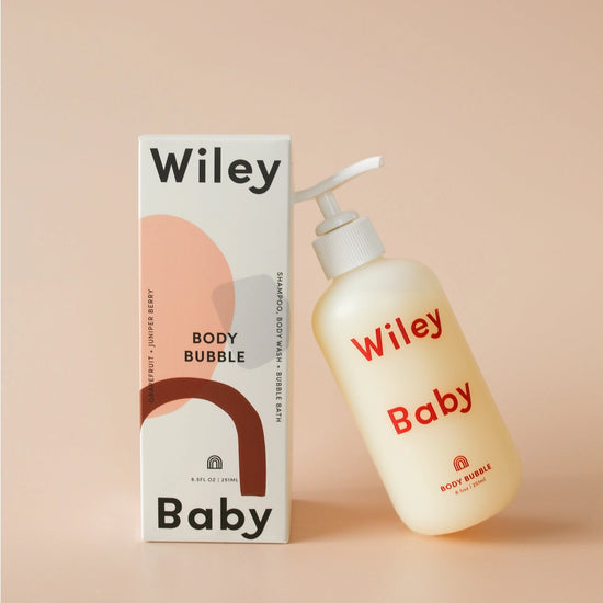 Wiley Baby Body Bubble cleanser bottle next to its packaging box, set against a solid peach-beige background.