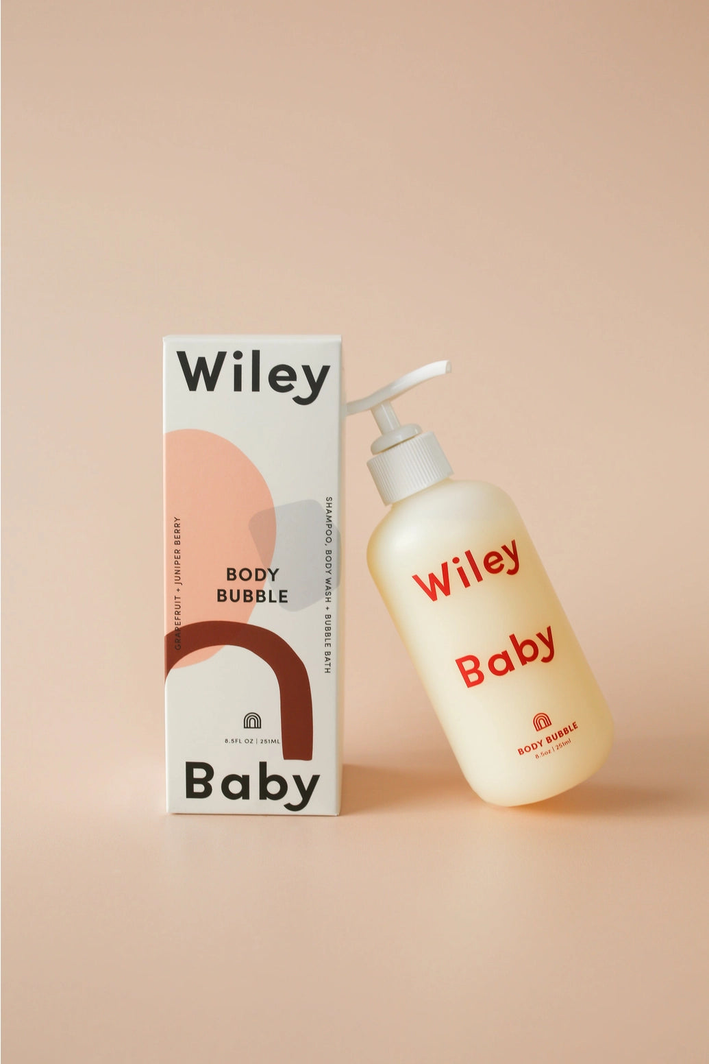 Wiley Baby Body Bubble cleanser bottle next to its packaging box, set against a solid peach-beige background.