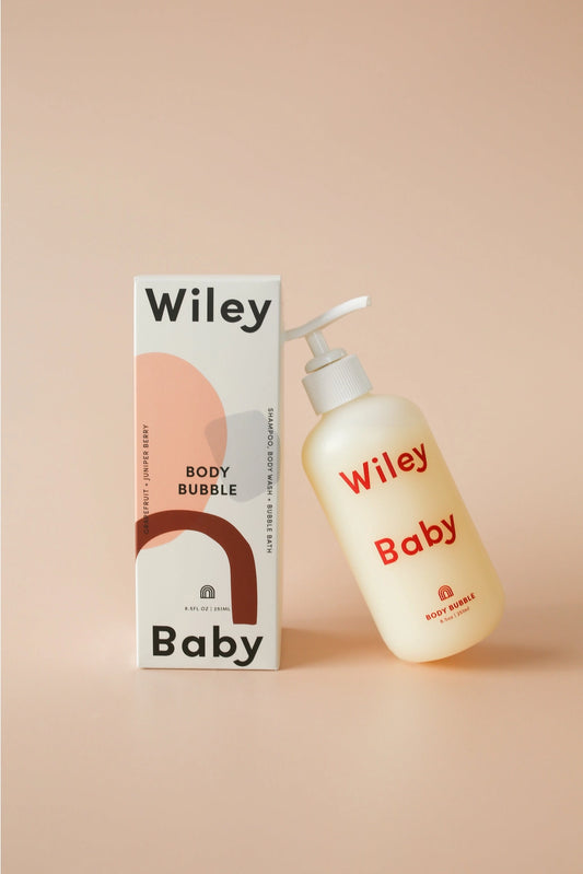 Wiley Baby Body Bubble cleanser bottle next to its packaging box, set against a solid peach-beige background.