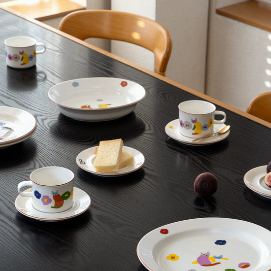 Set of ceramic tea cups and saucers with decorative patterns on a black table.