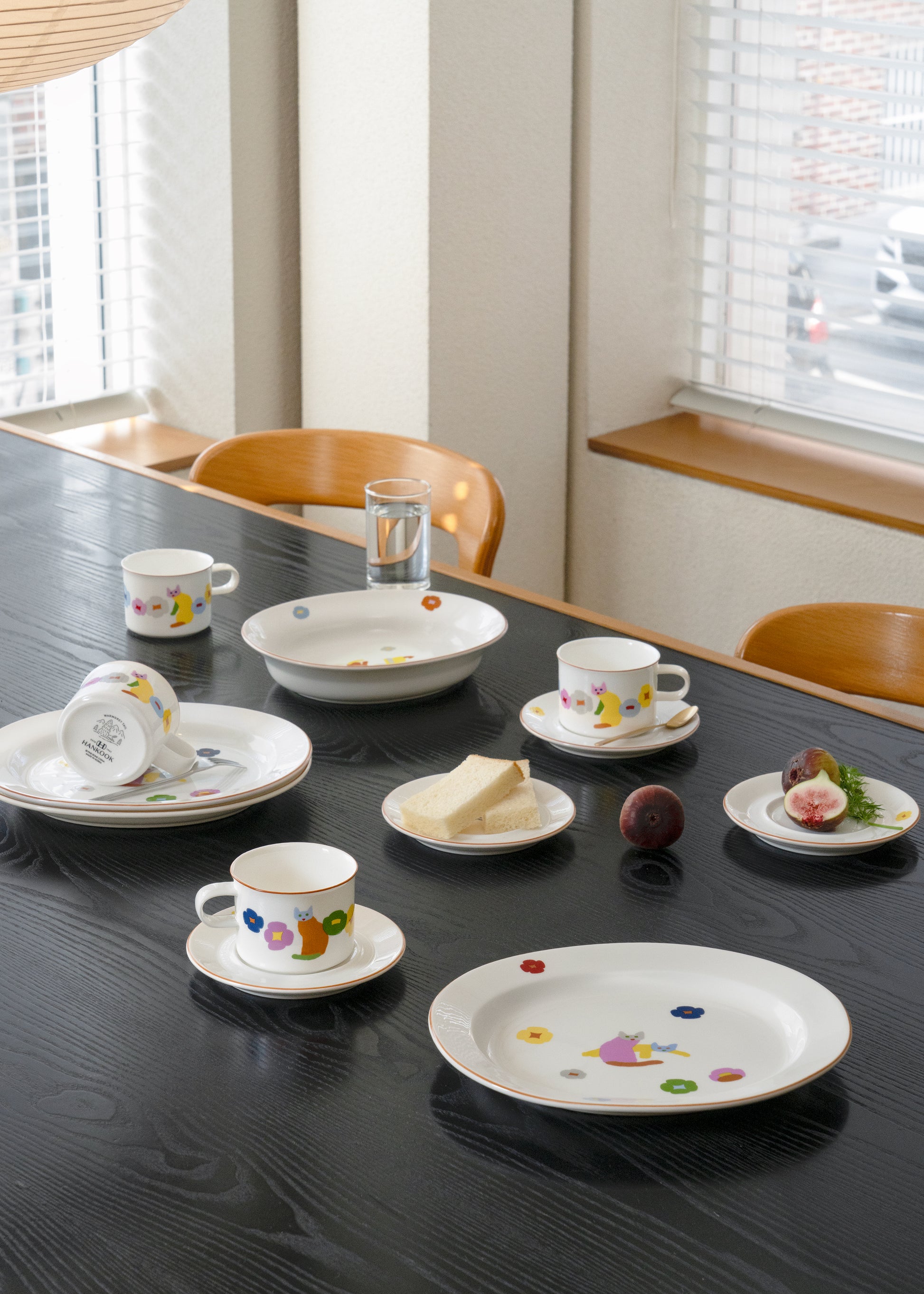 Dishes with patterns on a dining table with a glass of water and bread.