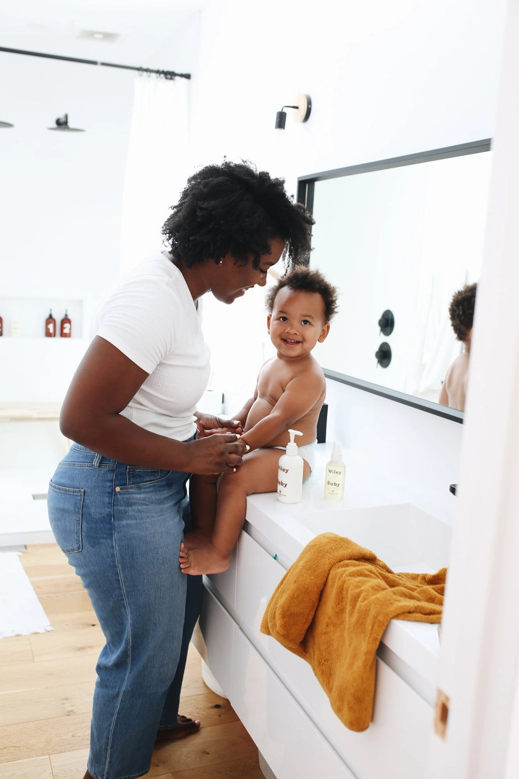 Woman and child in a bathroom with a yellow towel on a white surface.
