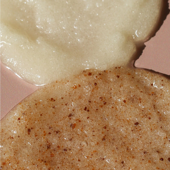 Close-up of two textured cosmetic or food-like substances on a pink surface: a pale creamy off-white mass at the top and a tan-beige speckled mass at the bottom.