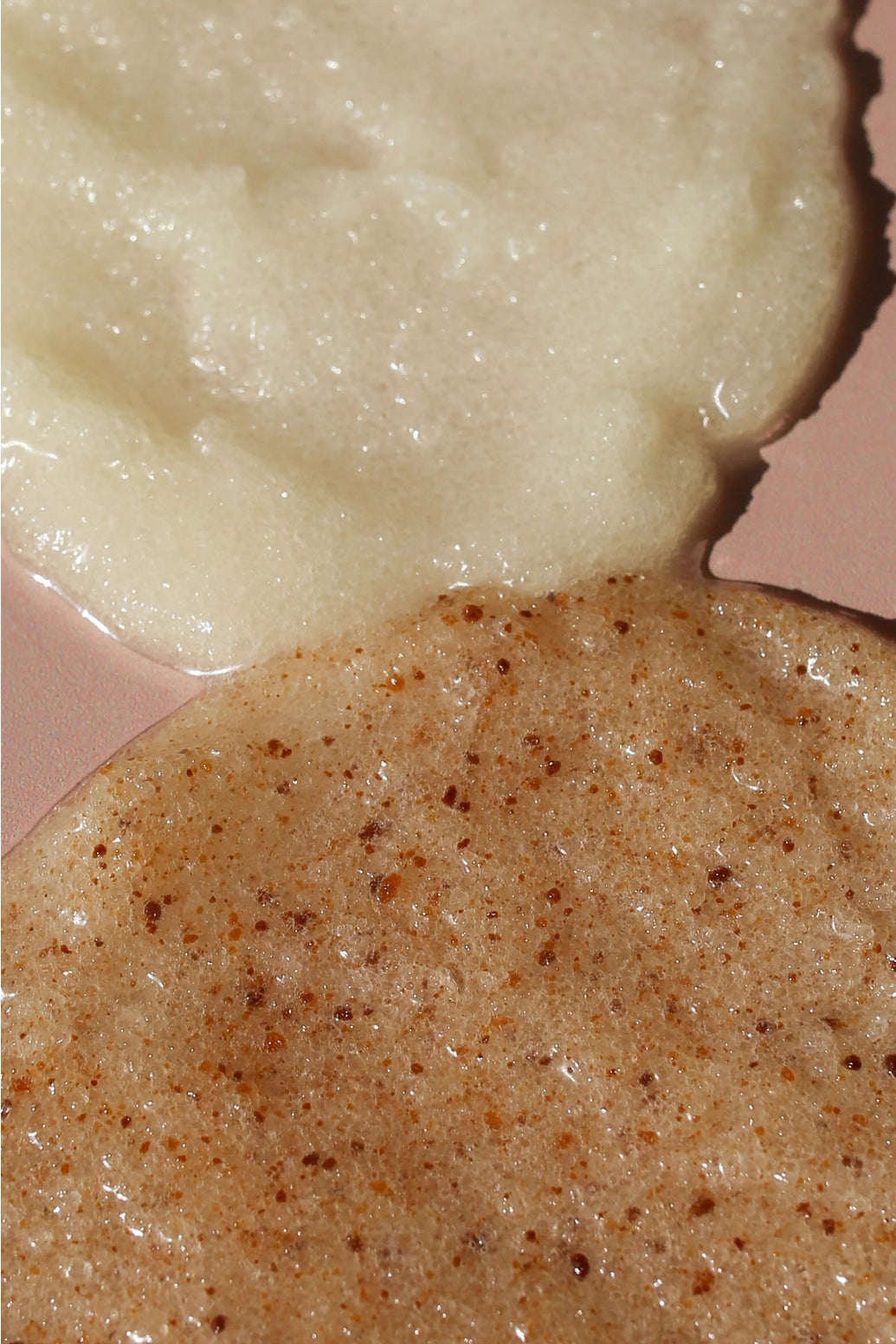 Close-up of two textured cosmetic or food-like substances on a pink surface: a pale creamy off-white mass at the top and a tan-beige speckled mass at the bottom.