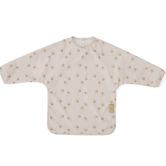 Child’s polyester cape bib covered in an all-over pale pink rabbit print, with long sleeves and a snap-closure at the back neckline spread flat against a white background