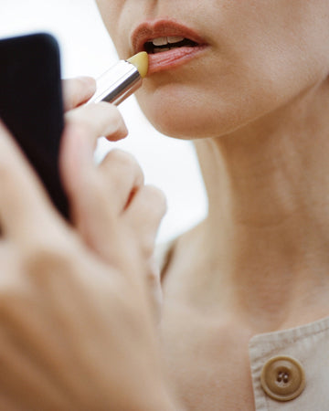 Person applying lip balm to their lips.