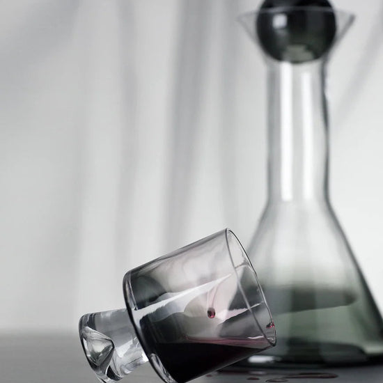 Clear glass decanter and wine glass with red wine on a neutral background